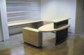Contemporary reception desk built with white maple and steel. The desk feaures a transaction top, an oval desktop, several file drawers, and additional work space behind the desk. The maple is natural with a commercial-grade protective finish, and the steel has a custom black patina.