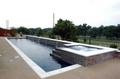 Straight line pool in Murphy with precast coping, sunstone plaster, raised back wall with brass scuppers