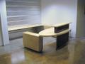 Contemporary reception desk built with white maple and steel. The desk feaures a transaction top, an oval desktop, several file drawers, and additional work space behind the desk. The maple is natural with a commercial-grade protective finish, and the steel has a custom black patina.