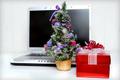 Image of computer next to a Christmas tree and gift