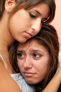 Teenage friends crying over unexpected teen pregnancy.